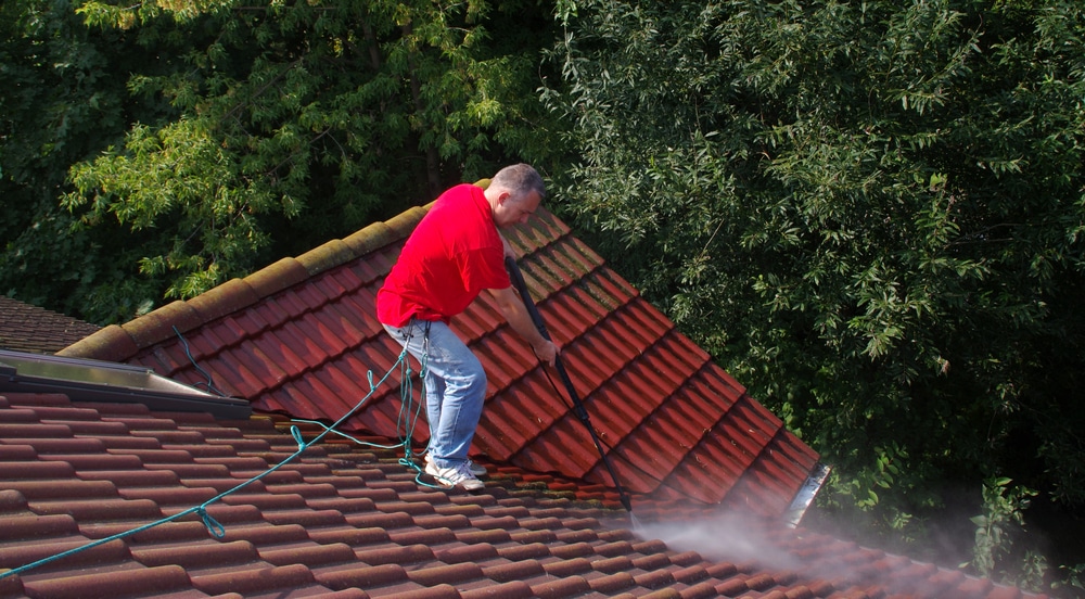 Roof repair and restoration in Melbourne, man pressure washing tiles.