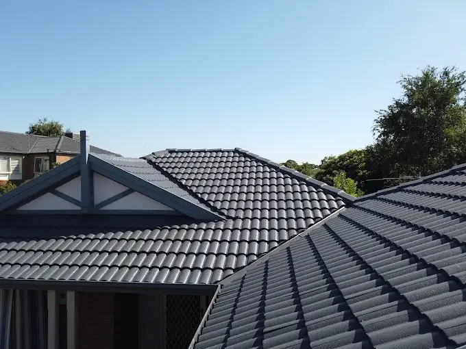 Dark grey concrete tile roof on a residential Melbourne home under clear blue sky.