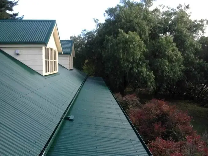 Green metal roof restored with fresh coating on a residential home.