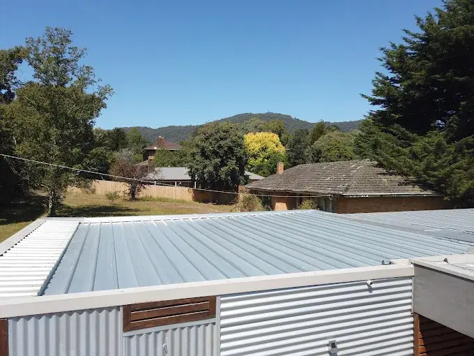 Restored metal roof on a residential property in Rowville under clear blue sky.