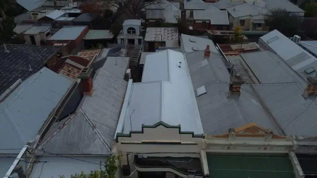 Restored metal roof with clean finish among older surrounding roofs.