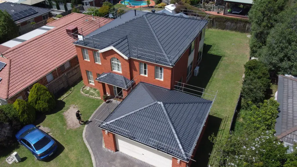 Sure! Here’s how I’d rewrite the alt text for a location page for Top Glaze Roofing Systems in, for example, Glen Waverley: Roof repair Glen Waverley: Aerial view of a two-story red-brick home in Glen Waverley with a dark gray tiled roof recently restored by Top Glaze Roofing Systems. Detached double garage and well-kept gardens visible; blue car parked in driveway with homeowner near entrance. Let me know if you need this adapted to another suburb or service (such as metal or Colorbond roofing)!.