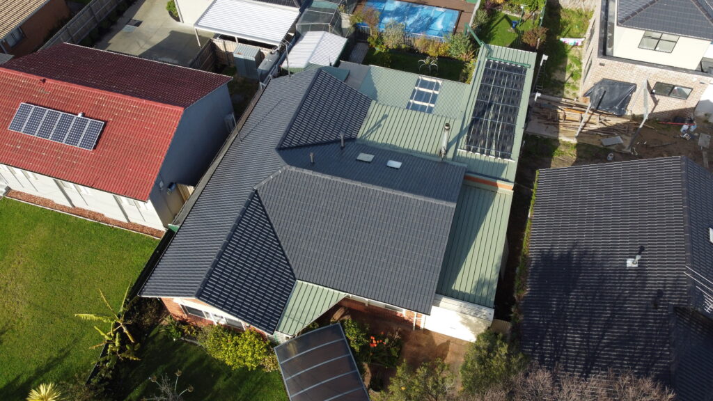 High-angle view of restored roof in Pakenham with visible tile repainting, ridge repairs, and uniform tile alignment across multiple roof sections.