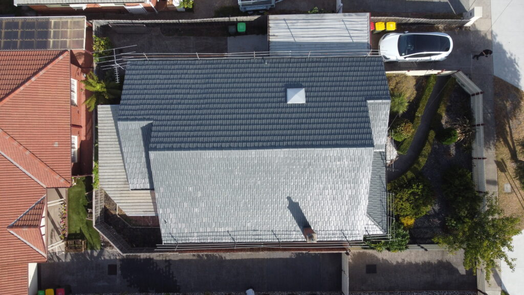 Aerial top-down view of a full roof repair in Bentleigh East showing consistent tile placement, ridge re-pointing, and surrounding garden pathways.