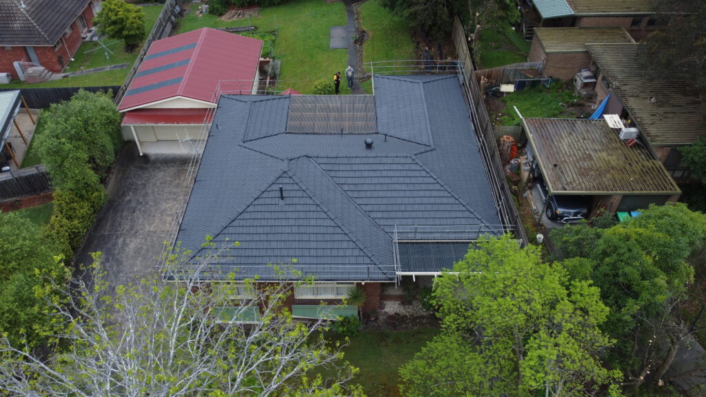 Top-down view of completed roof repair in Ringwood showing sealed tiles, ridge alignment, and a maintained garden landscape surrounding the home.