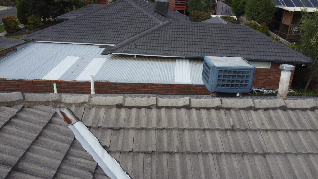 Damaged tiled roof in Dandenong before repair, showing worn ridge and cracked tiles.