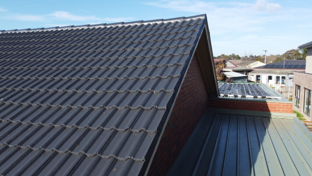 Side profile of a gable-style tile roof in Pakenham after tile roof repairs, featuring dark-coloured tiles and clean finish at the edge lines.