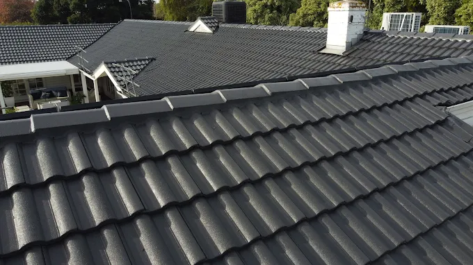 Freshly repaired tile roof with restored ridge caps and uniform dark grey tiles on a residential property.