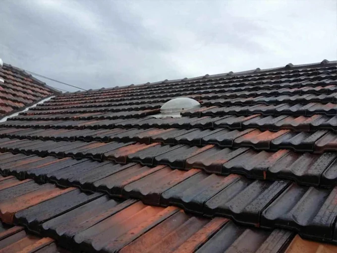 Weathered tile roof with visible wear and fading, showing areas in need of repair and restoration.